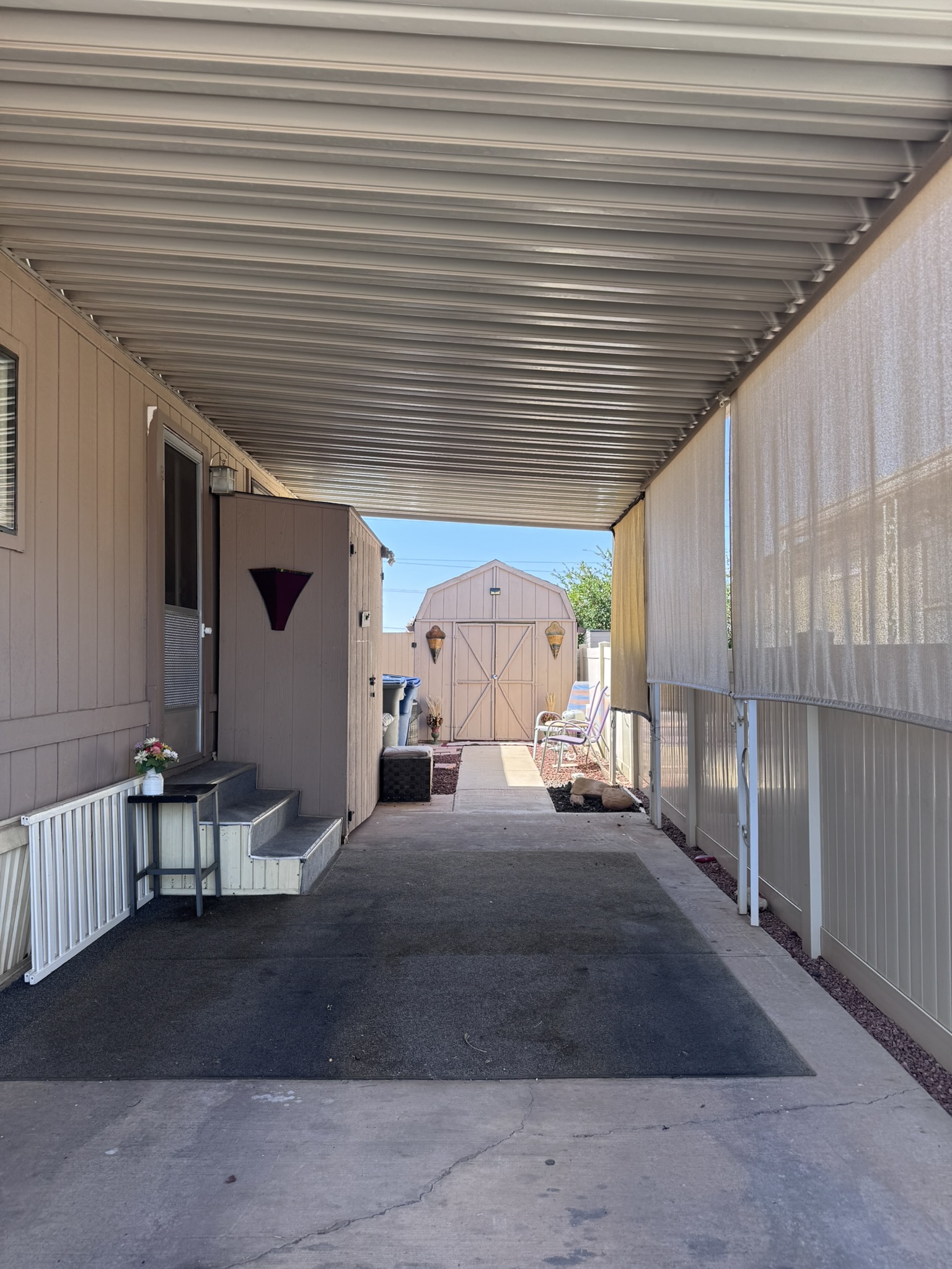 The full-length covered parking — with storage shed beyond